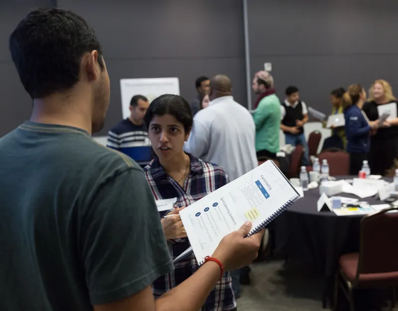 Two workshop participants discussing sprint planning from a course workbook